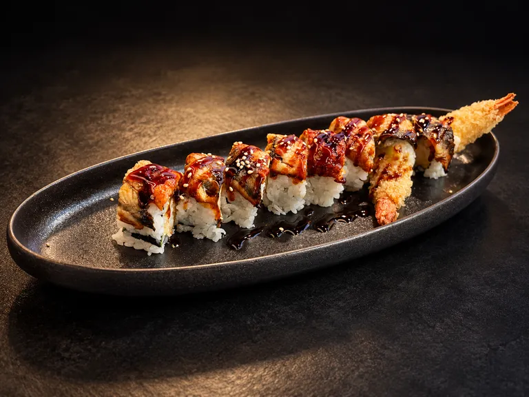 Aburi Eel Maki with glazed eel, sesame seeds, and shrimp tempura on a black platter