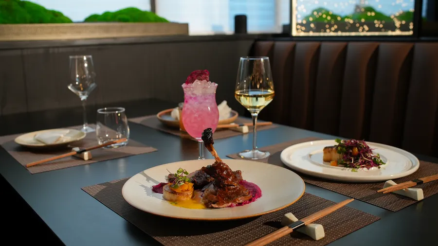 Niku dinner table with plated entrées, a pink cocktail, and wine