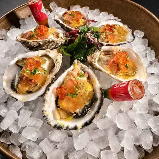 Fresh oysters with tomato garnish served over ice