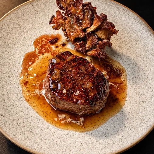 Seared Harmony Filet with crispy oyster mushrooms on a white plate