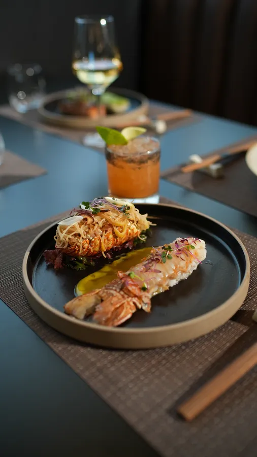 Lobster Noodle Celebration with South African lobster and garlic shoyu noodles on a black plate