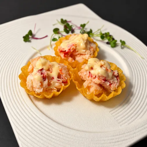 Three lobster tartlets with lemon mayo on a white plate