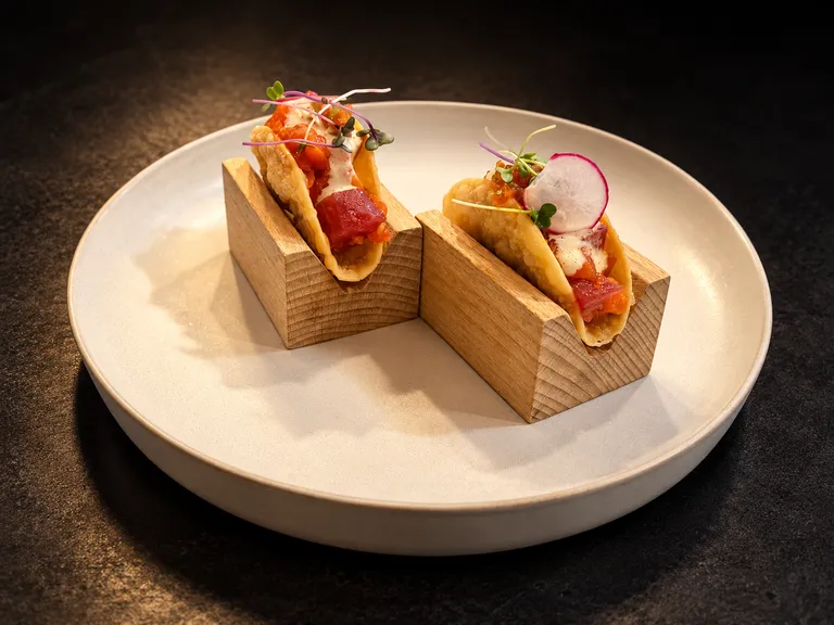 Two Sashimi Tacos in wooden holders on a white plate