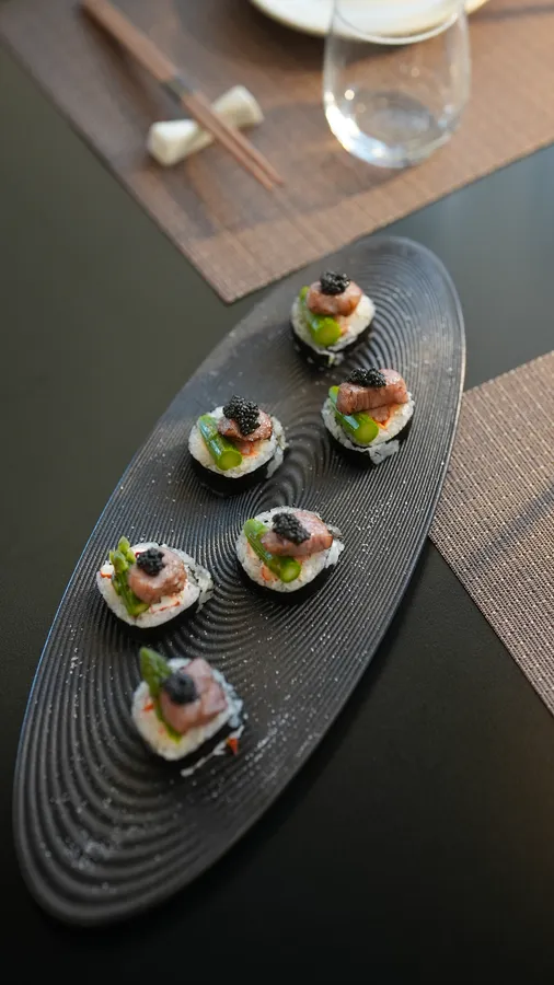 Six pieces of Land and Sea Maki with lobster, asparagus, seared A5 wagyu, and caviar on a black platter