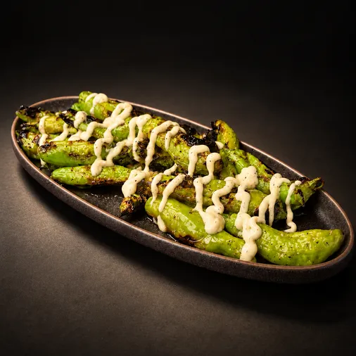 Charred shishito peppers drizzled with yuzu aioli