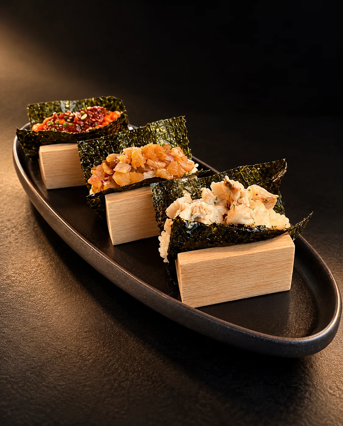Three nori hand maki served on a black platter